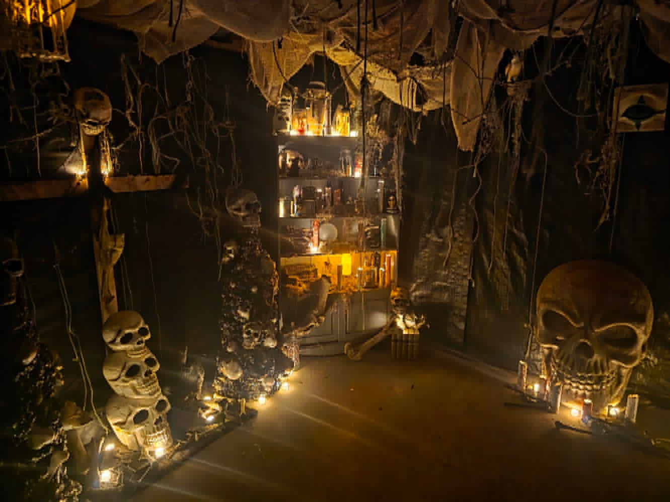 A dimly lit themed room inside The Carver&rsquo;s Curse haunted attraction at Barberry Farm in Brooklyn, Connecticut, with stacked skulls, candles, and cobwebs